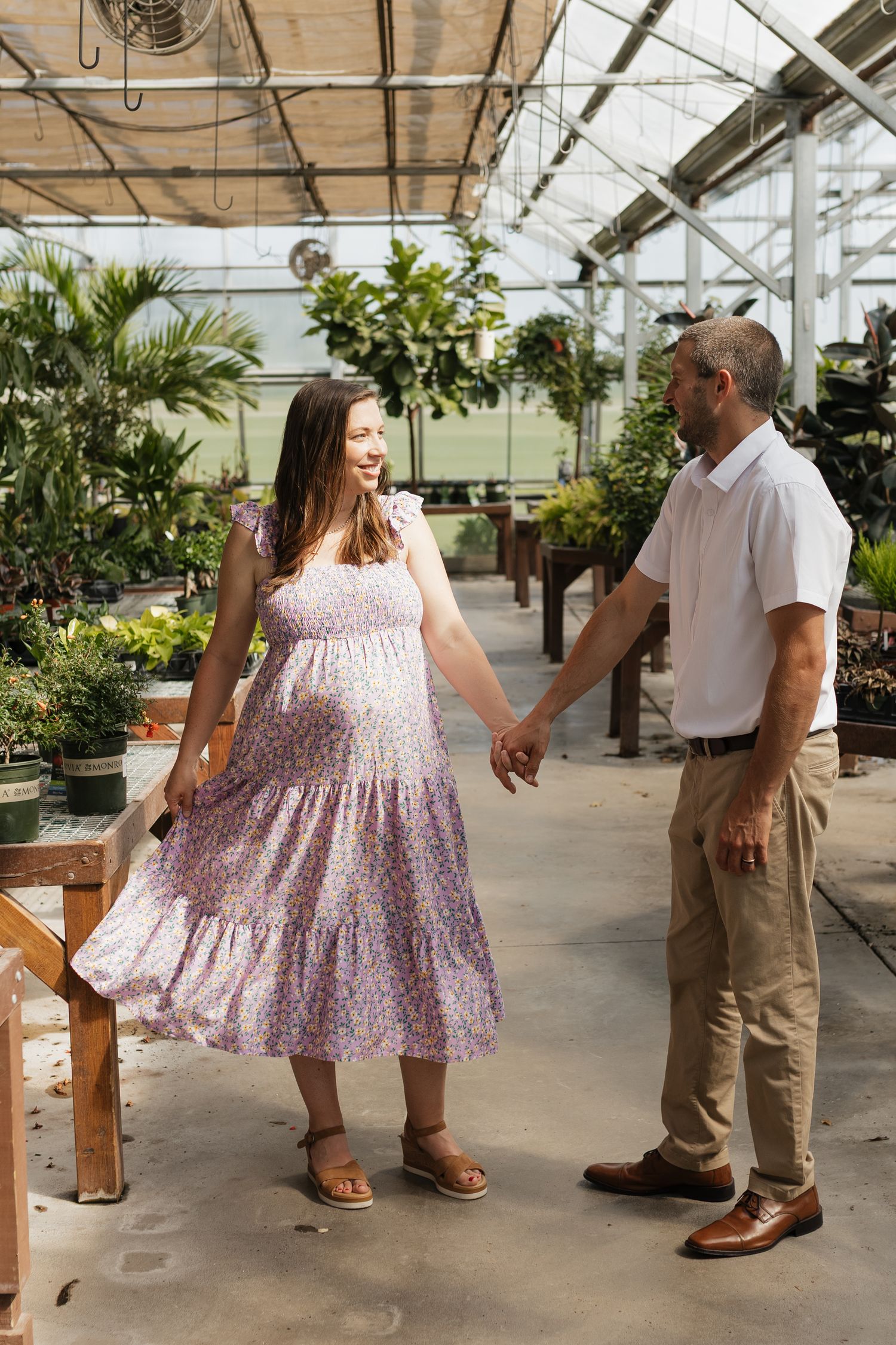 Dancing couple in casual attire showing joyful movements in a greenhouse setting.