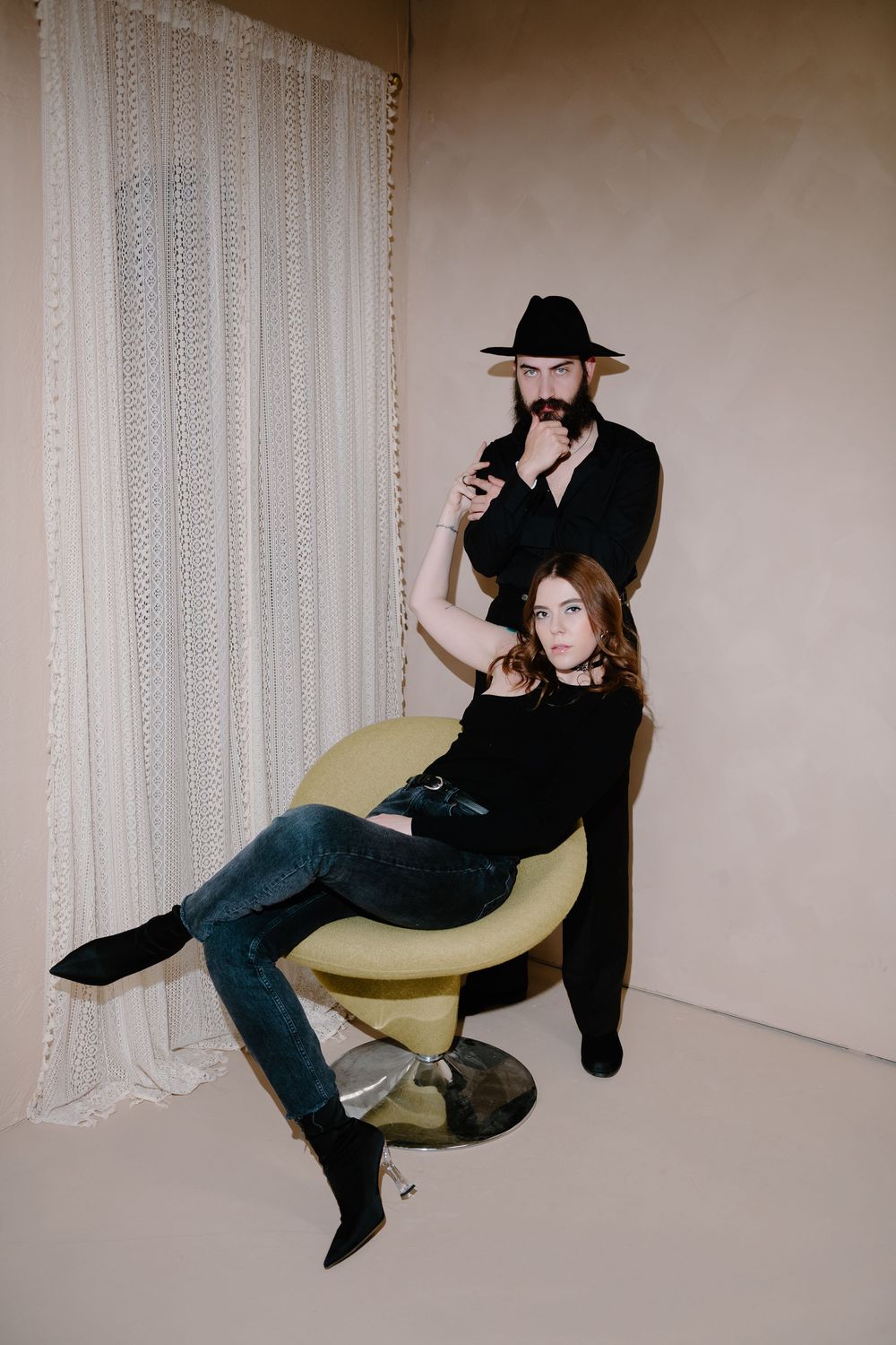 A sequence of four artistic photos showing two people lounging on a yellow chair against a white curtained backdrop.