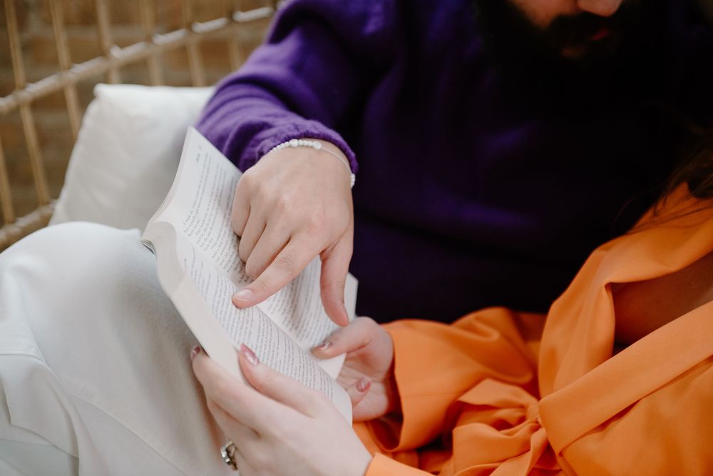 Close-up view of hands sewing orange fabric on a sewing machine showing detailed stitching work.
