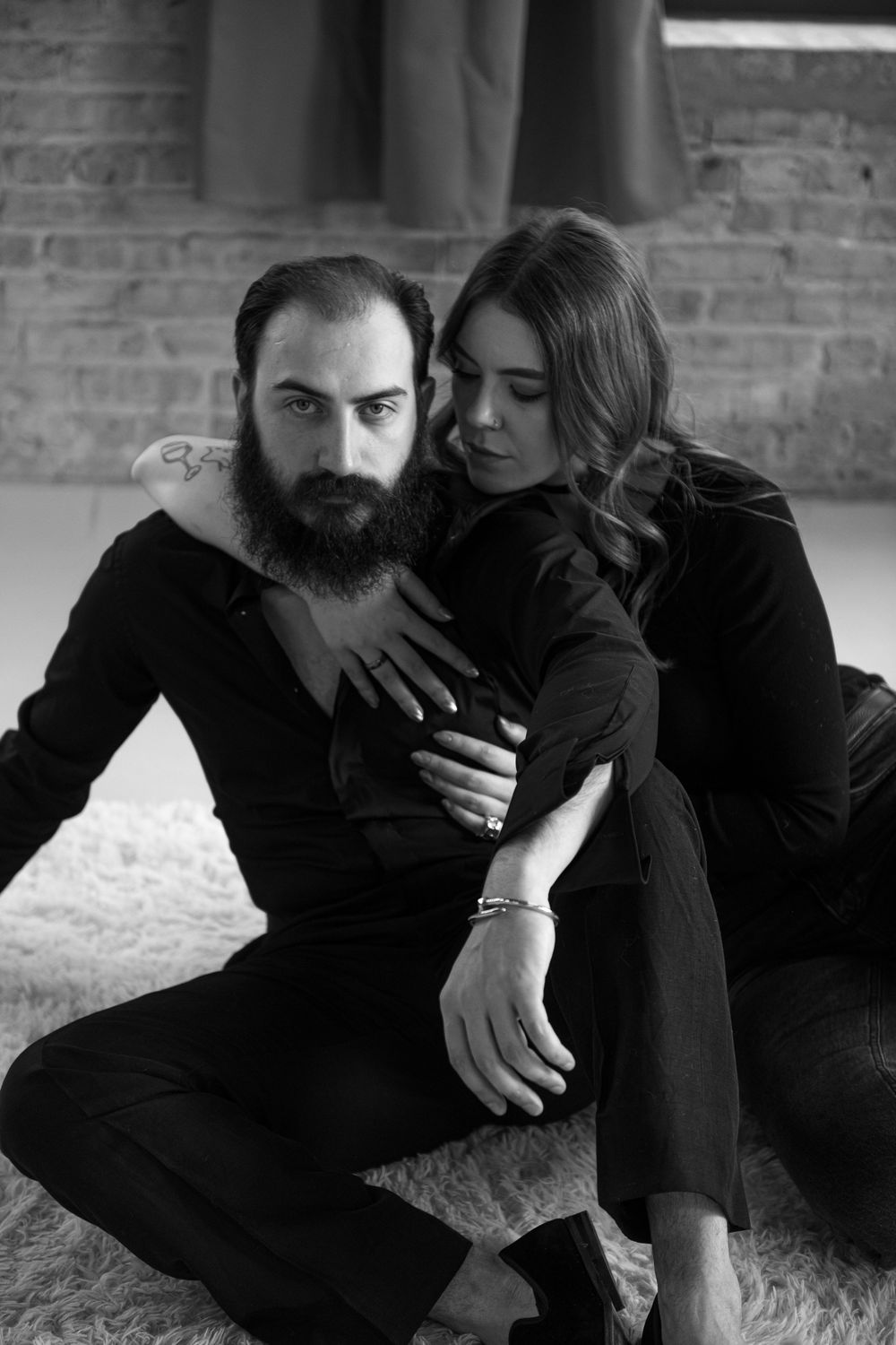 A romantic black and white photo series showing a couple in dark clothing embracing on a carpeted floor.