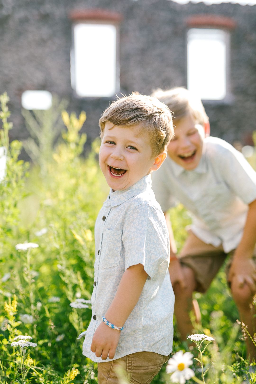 Children playing and laughing together in a sunny wildflower meadow on a bright summer day.
