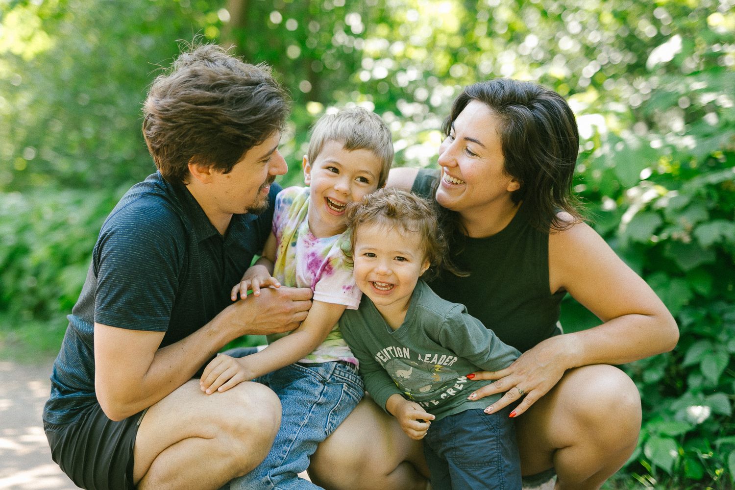 A loving family shares playful moments together while relaxing outdoors in a lush green garden setting.