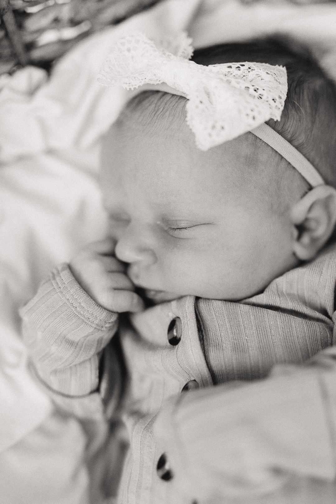 Black and white close-up photo of a sleeping newborn baby wrapped in delicate lace.