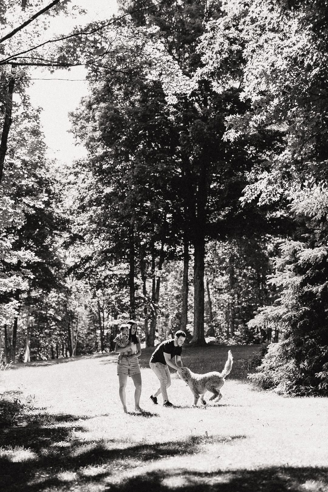 A group plays together in a sunny wooded area, creating a nostalgic black and white scene.