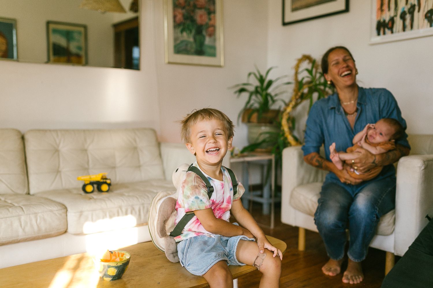 Candid moments of family playtime and laughter in a bright living room with white furniture.