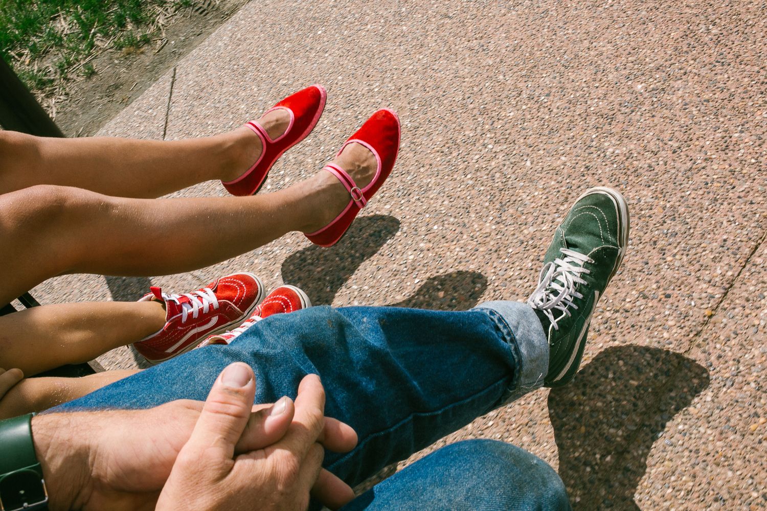 Close-up of colorful sneakers and shoes arranged on textured concrete surface.