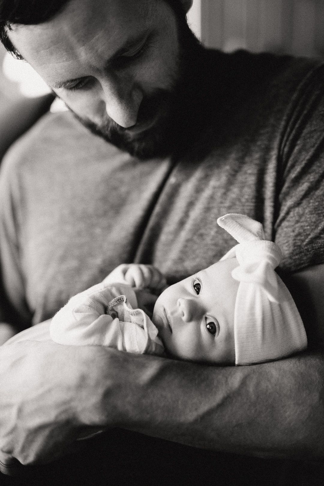 A tender black and white photo series showing a parent cradling and bonding with their newborn baby.