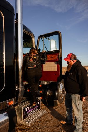 Farmers work together inspecting equipment and machinery on a farm field during sunset.