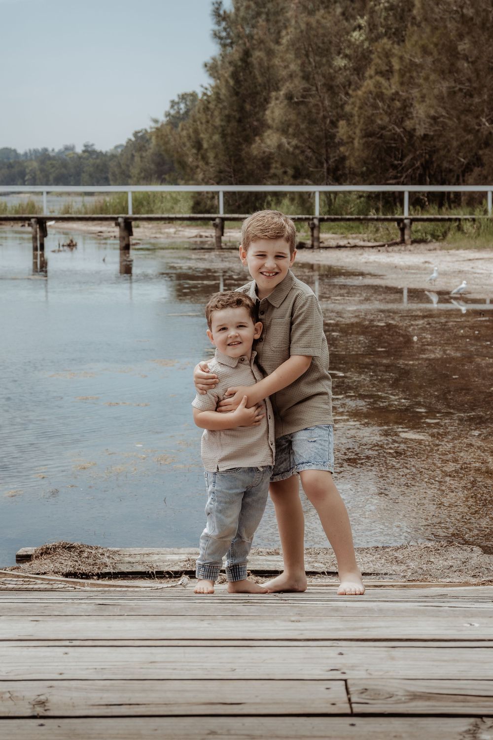 Playful moments captured between siblings on a lakeside dock.