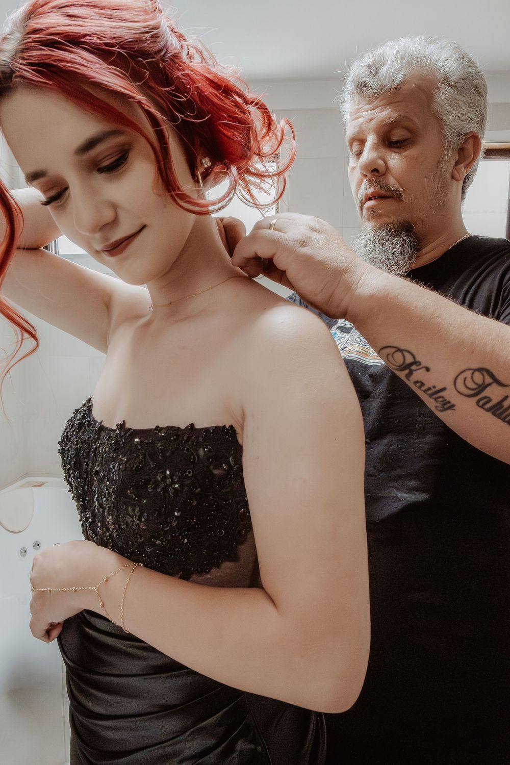 Final touches being added to formal hairstyle with elegant black dress and red hair.