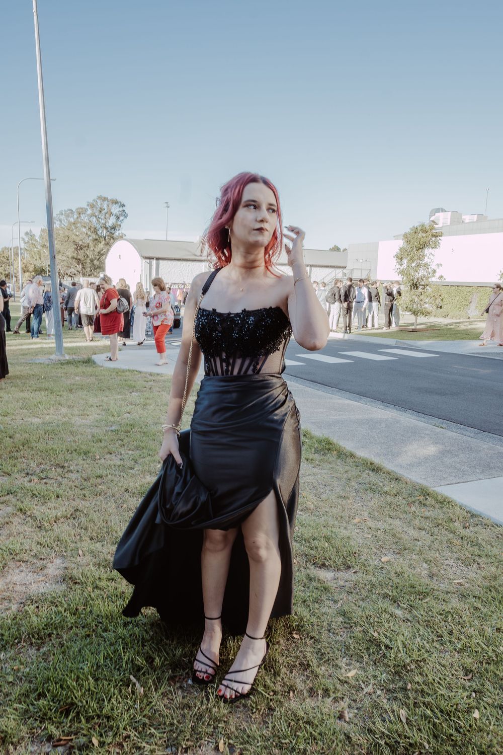 A black dress is showcased in a series of outdoor poses on grass.