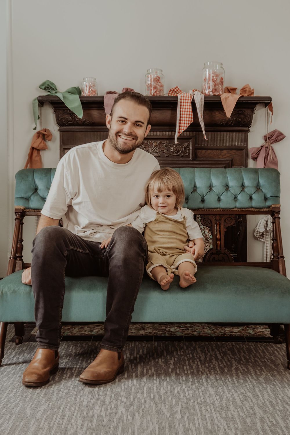 A parent and child sit together on a teal vintage bench with rustic decor at a hunter valley christmas photoshoot.