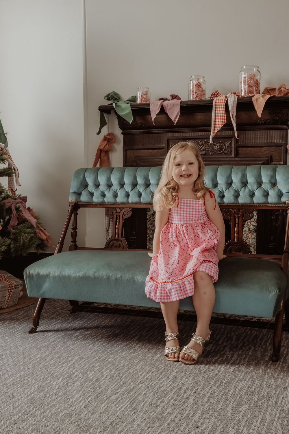 A little girl sitting on a teal blue couch at a hunter valley christmas photoshoot.