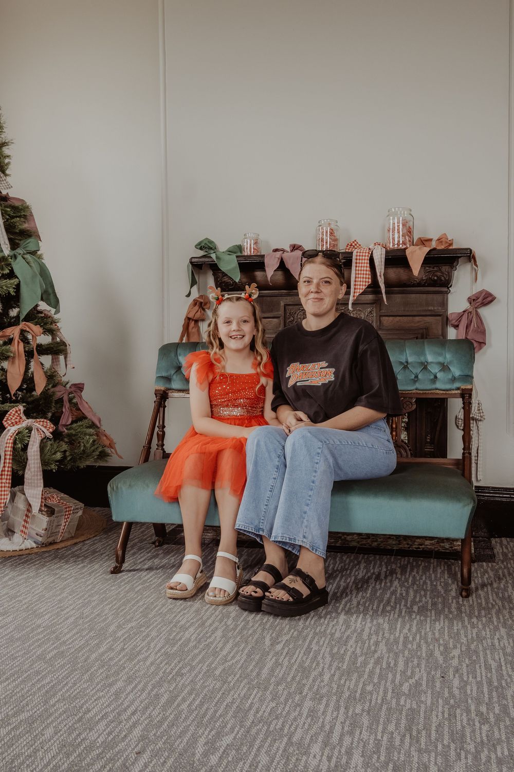 A mother and daughter sitting on a vintage teal bench at a hunter valley christmas photoshoot.