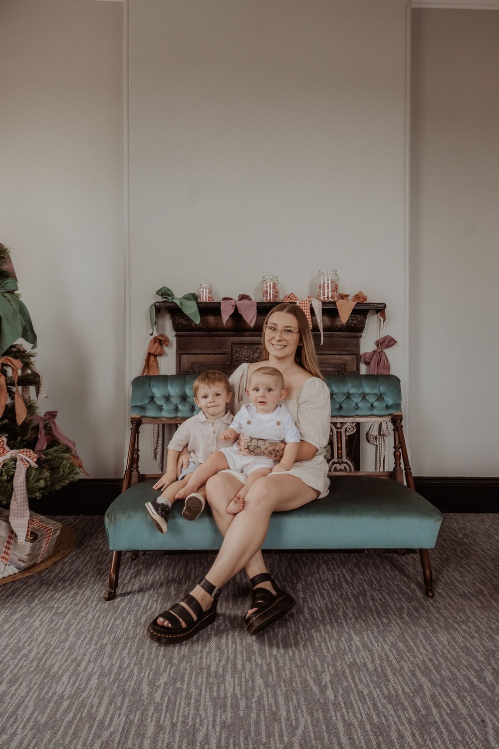 A family sitting together on a teal blue couch in a christmas themed indoor setting at a hunter valley christmas photoshoot.