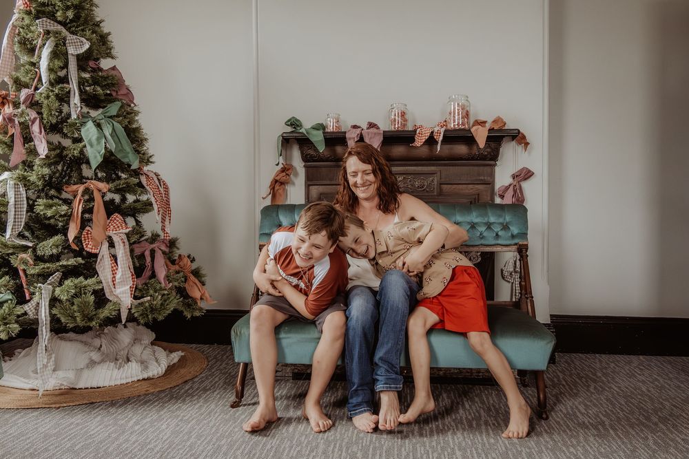 Family having fun together on a teal vintage bench with Christmas tree in cozy living room setting at a hunter valley christmas photoshoot.
