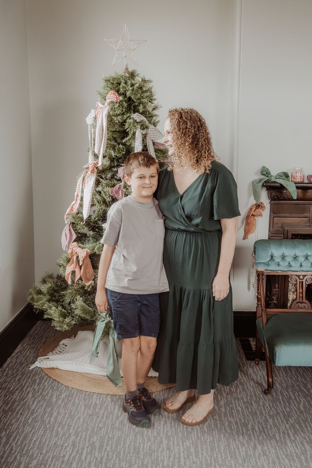 A festive scene with a Christmas tree, vintage furniture and two people standing together at a hunter valley christmas photoshoot.