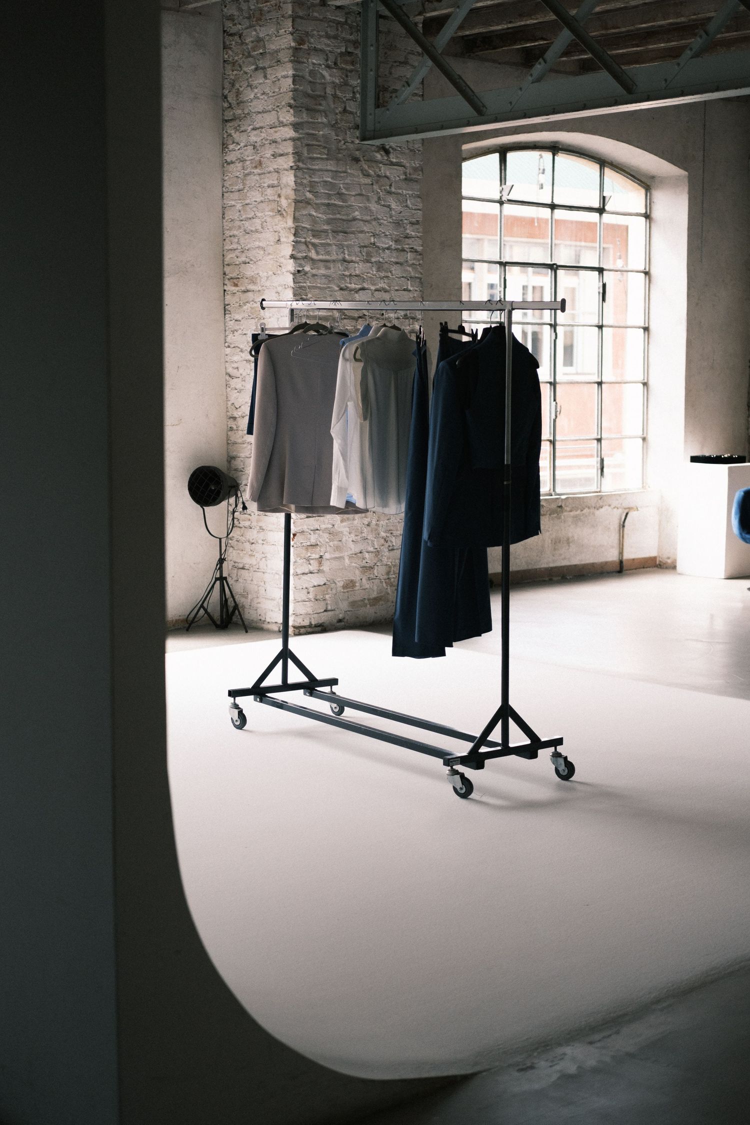 A photo studio setup with white seamless backdrop and lighting equipment in an industrial loft space with brick walls.