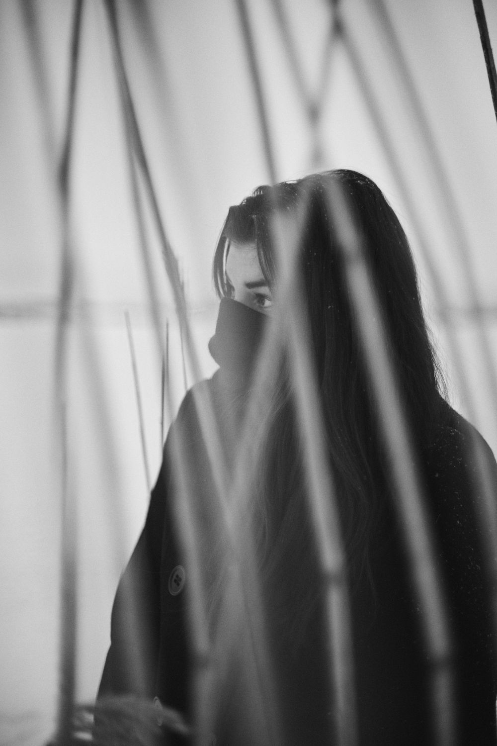 Dramatic black and white portrait of silhouettes behind sheer curtains creating an artistic ethereal effect.