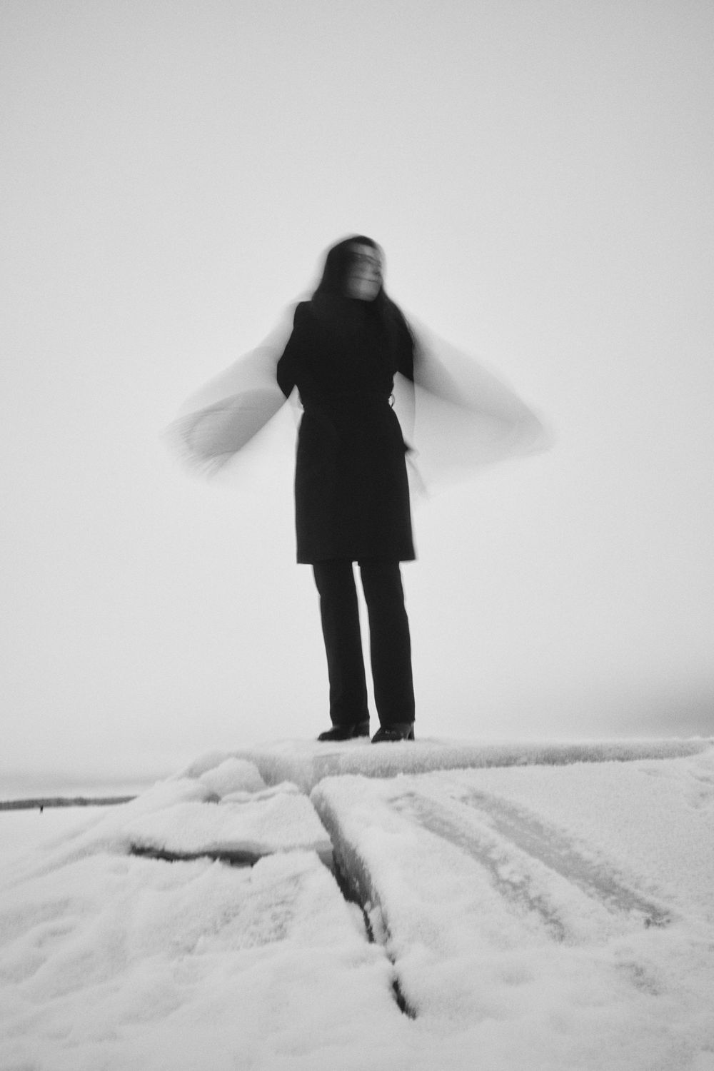 A sequence of black and white photos showing a figure standing in deep snow creating a minimalist winter scene.