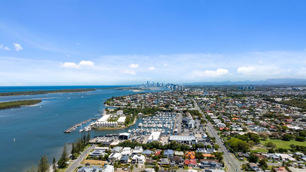 Aerial panorama of a coastal city with marina, buildings and waterfront developments.