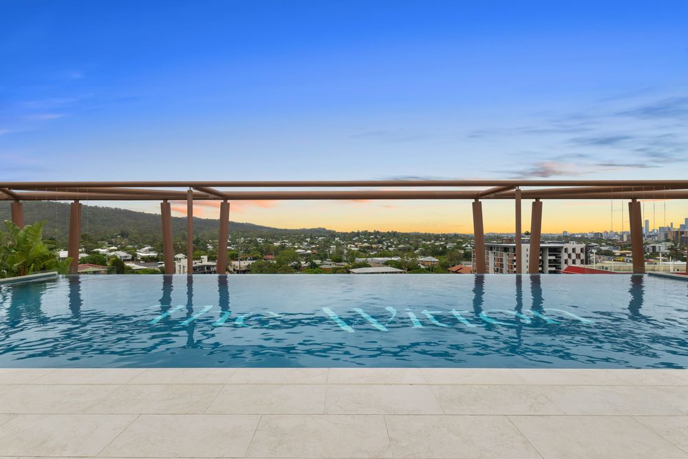 Infinity pool edge overlooking scenic waterfront views during sunset.