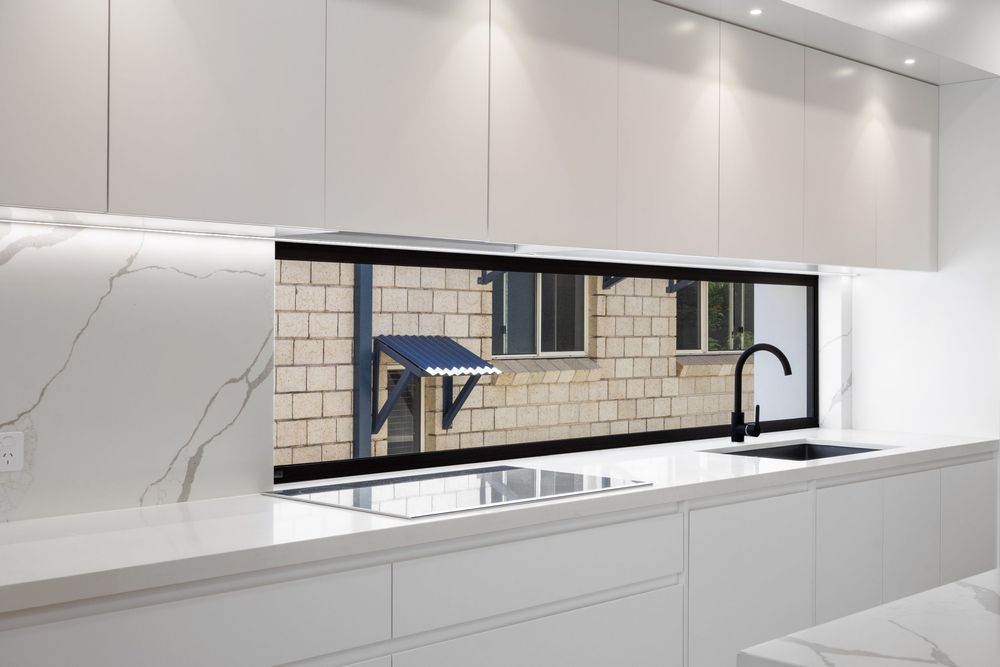 Minimalist white kitchen featuring subway tile backsplash and seamless cabinetry.