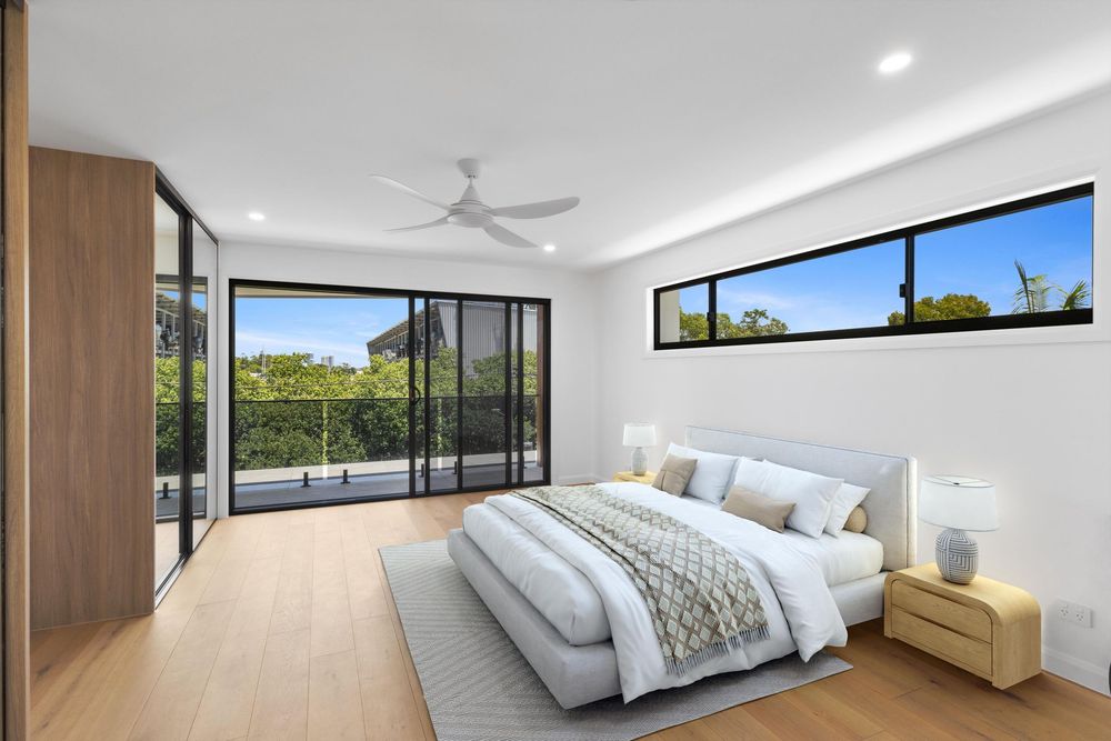 Modern apartment interior with white walls, wooden floors, and large windows offering natural light and city views.