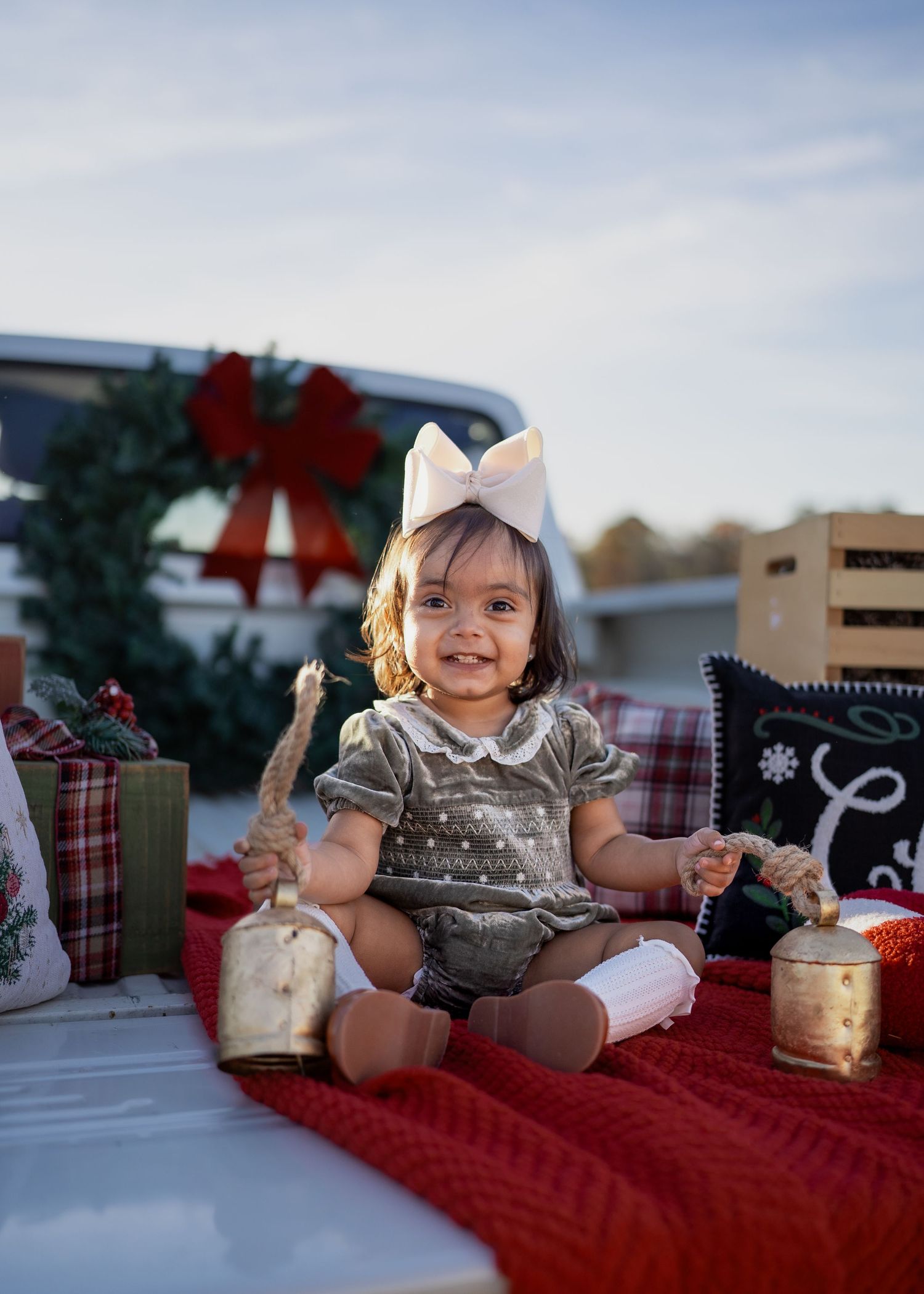 Family enjoying a festive Texas farm Christmas mini session, sitting on the bed of an old red Ford truck decorated with holiday greenery.