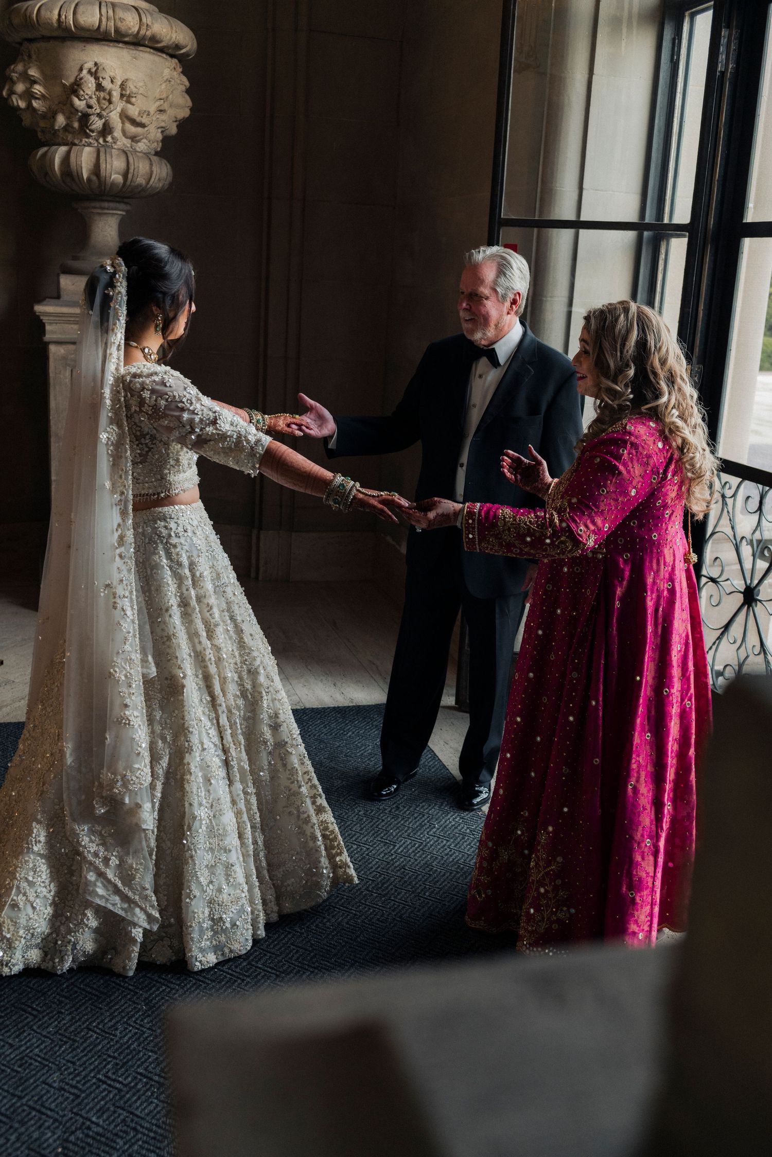 First look between a bride and her parents at Cuneo Mansion entrance.
