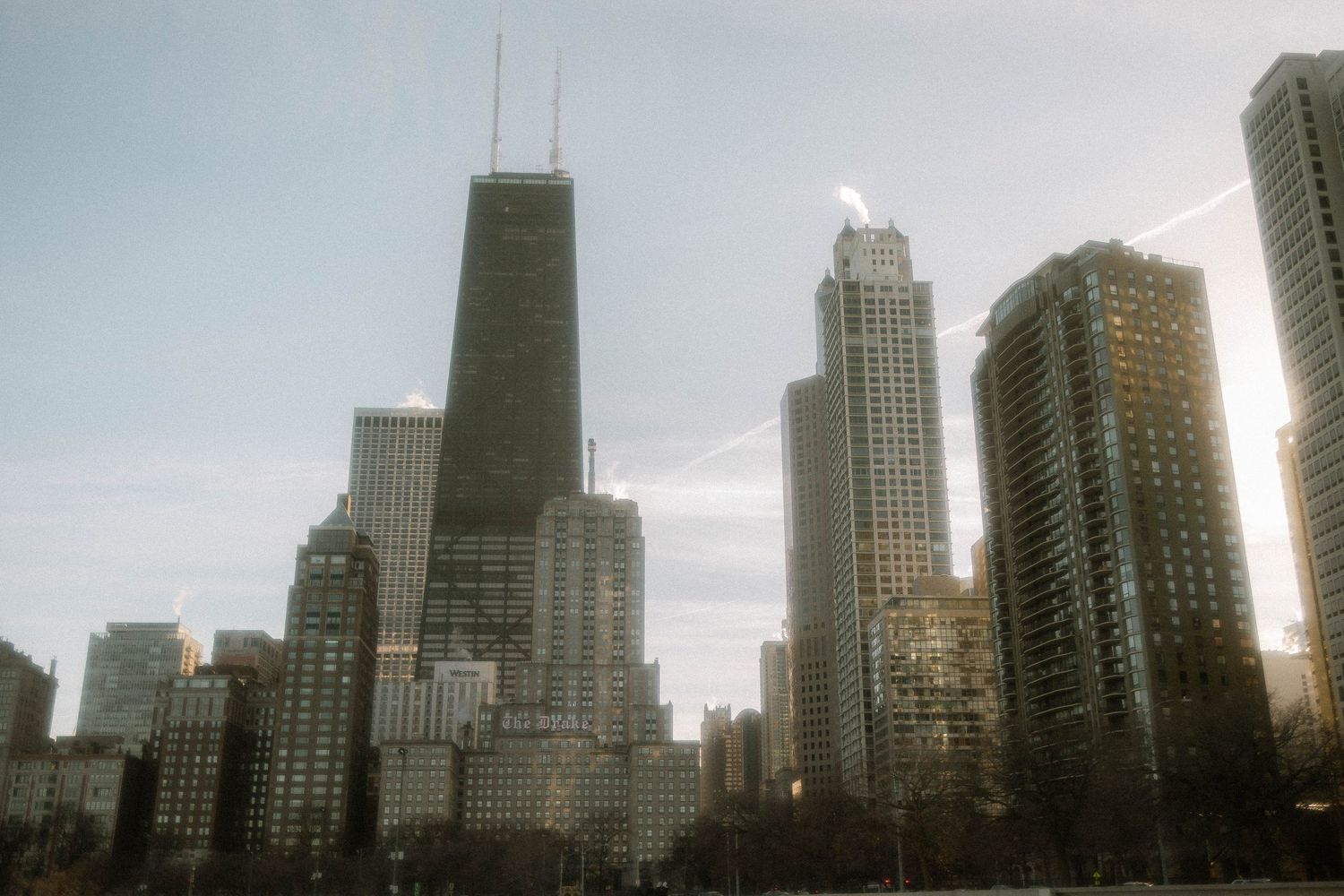 Chicago skyline at sunset featuring the iconic John Hancock Center and surrounding high-rise buildings along Lake Shore Drive.