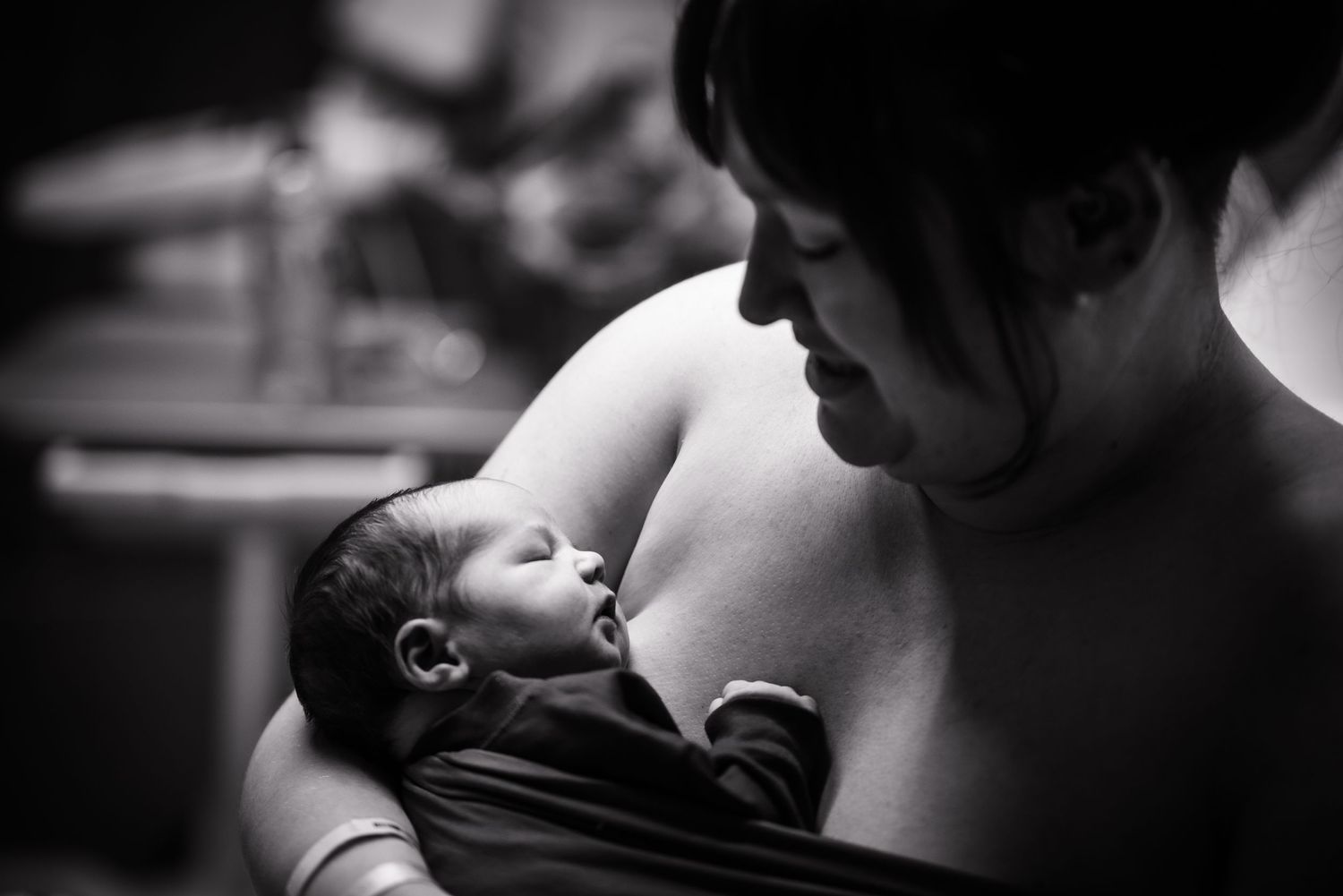 A black and white photo captures an intimate moment between a mom and her newborn sharing a tender kiss at the Toledo Hospital.