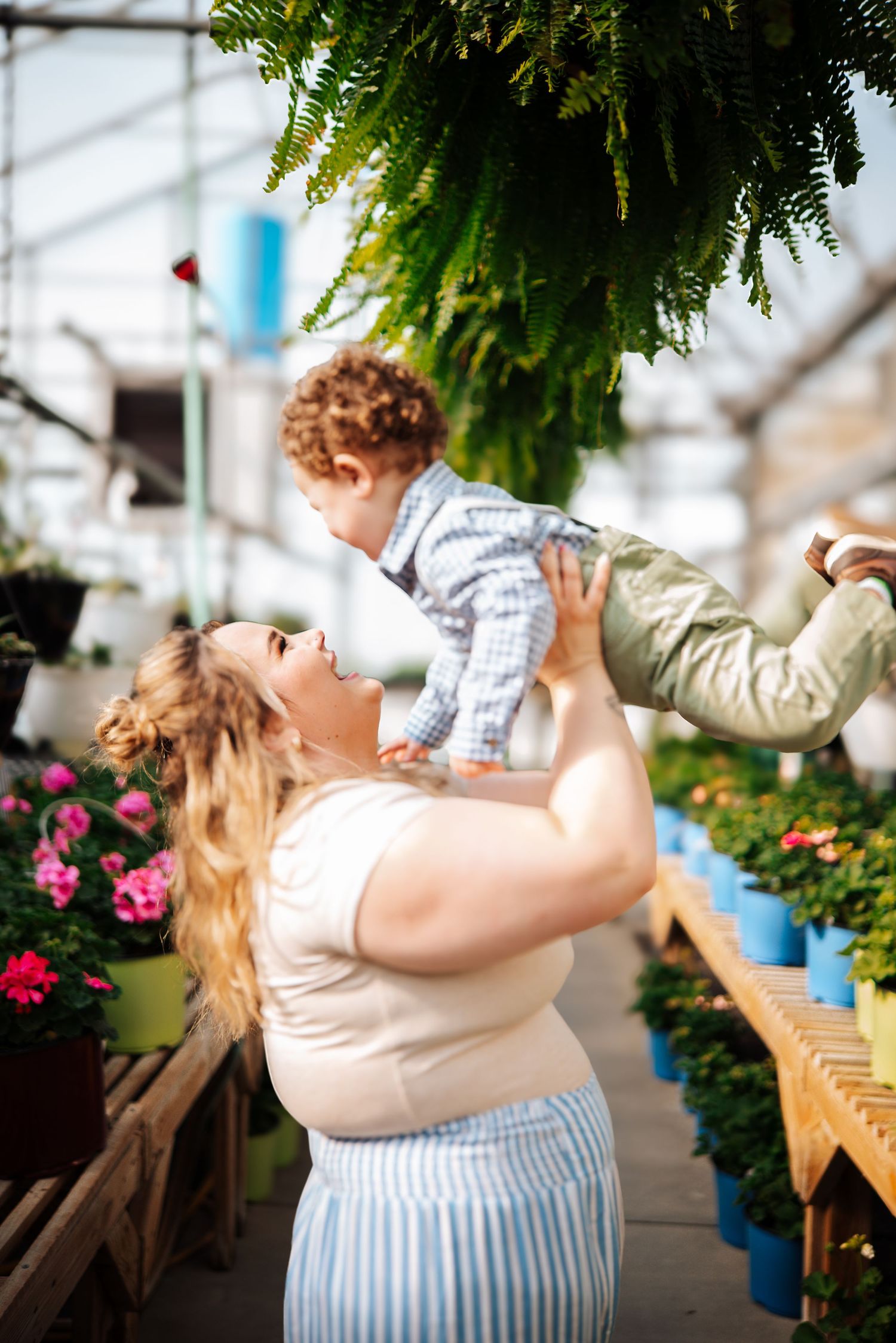 Two people dancing together in Wolfe's greenhouse in Bowling Green, Ohio surrounded by hanging plants and pink flowers.