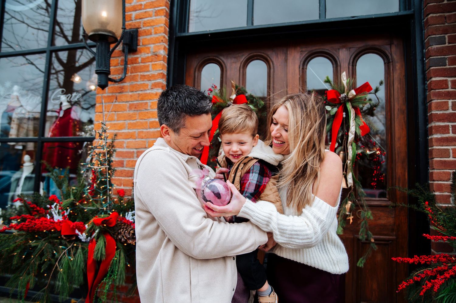 A couple shares a romantic moment together in front of a brick building decorated with red holiday flowers downtown Grand Rapids Ohio.