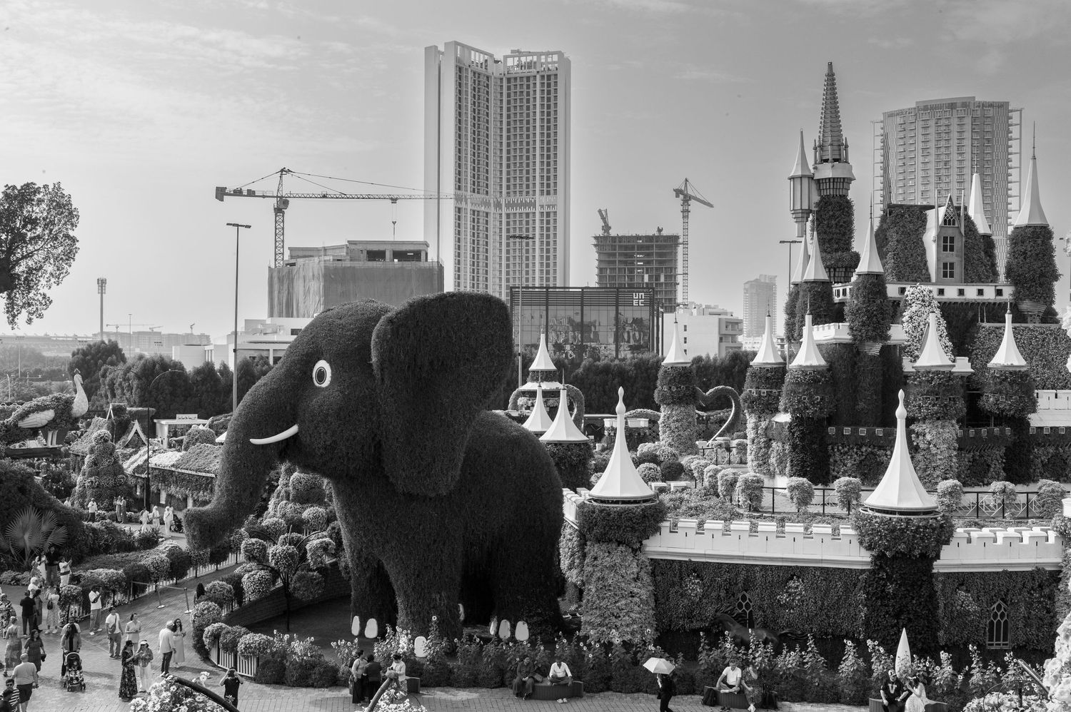 Black and white vintage photo of a large elephant-shaped structure at a theme park with city buildings in the background.