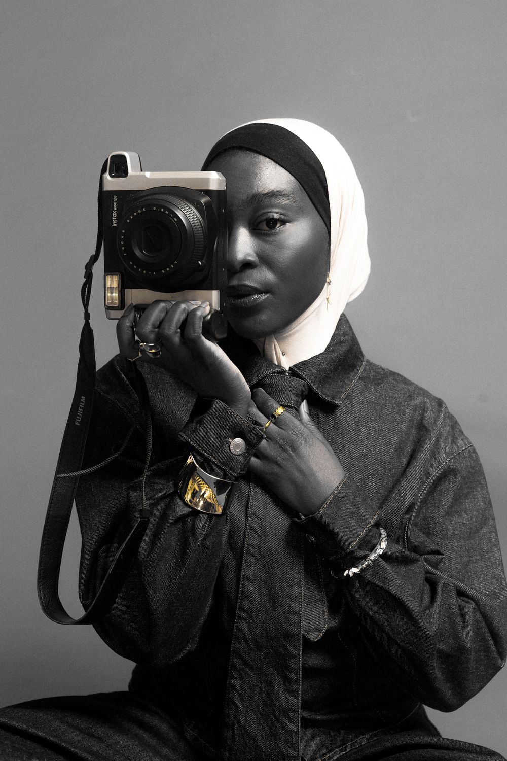 A series of black and white photos showing a photographer using a professional camera while wearing a white head covering.