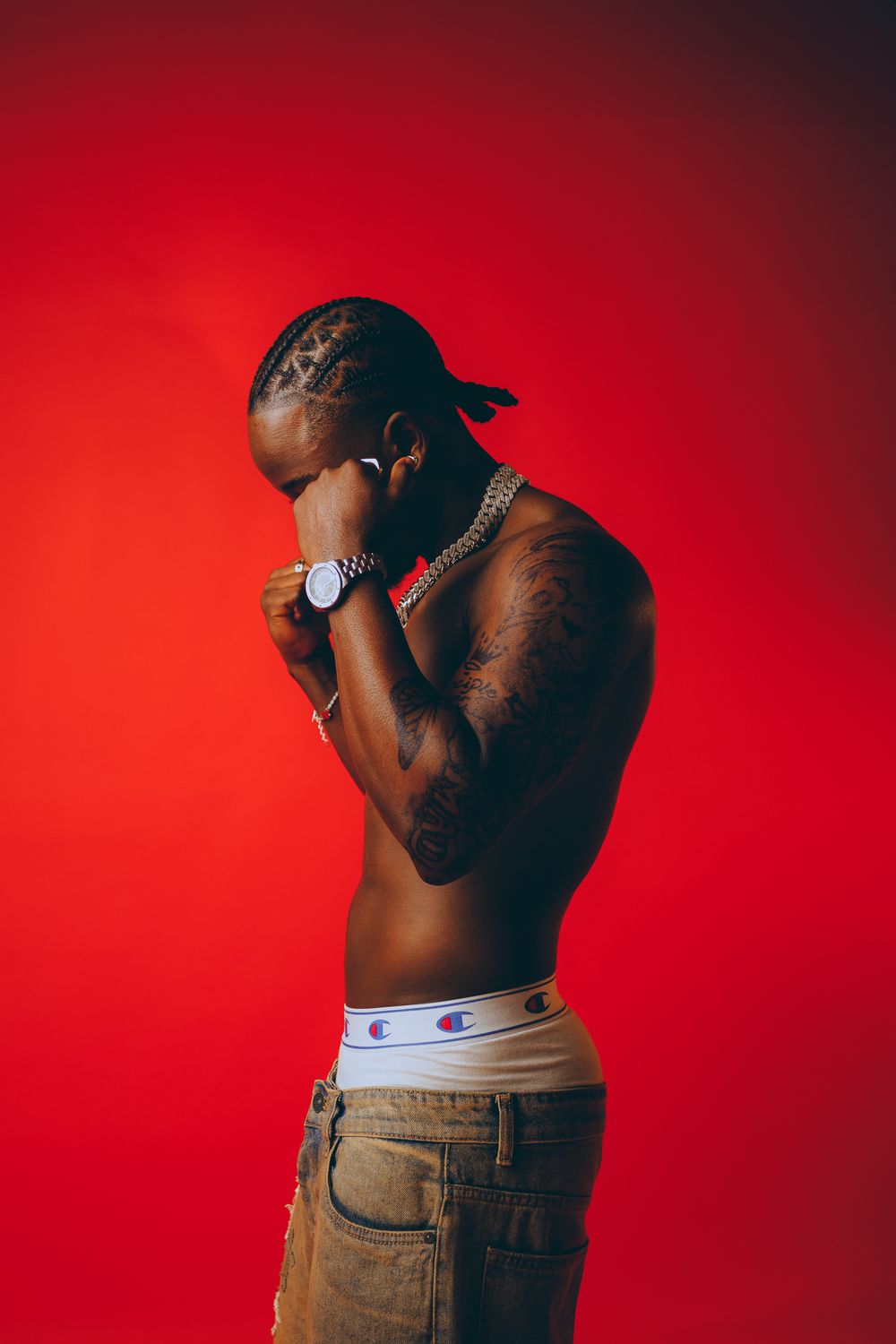 Artistic portrait series against red backdrop showing shirtless person in jeans from different angles.