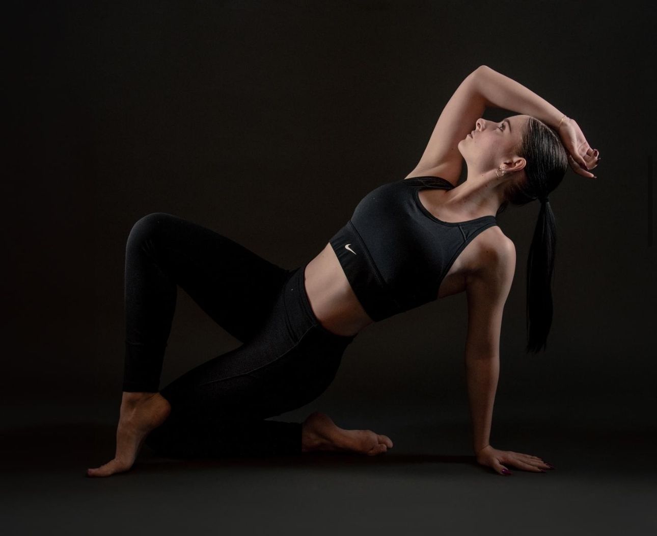 A dancer performs a dramatic split leap against a dark background, showcasing strength and grace in mid-air motion.