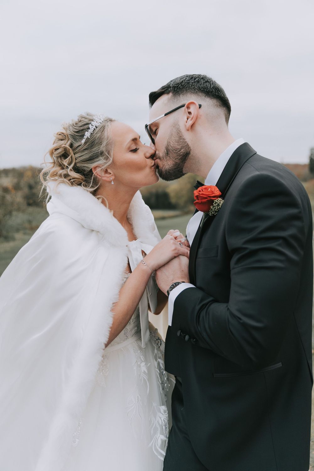 Romantic wedding couple sharing tender kisses in a sequence of four outdoor portraits against an overcast sky.