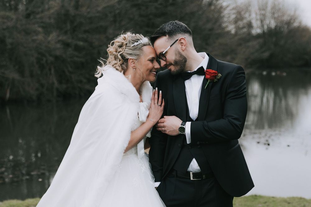 Winter wedding couple shares intimate moments by a snow-covered lake in romantic outdoor photo series.