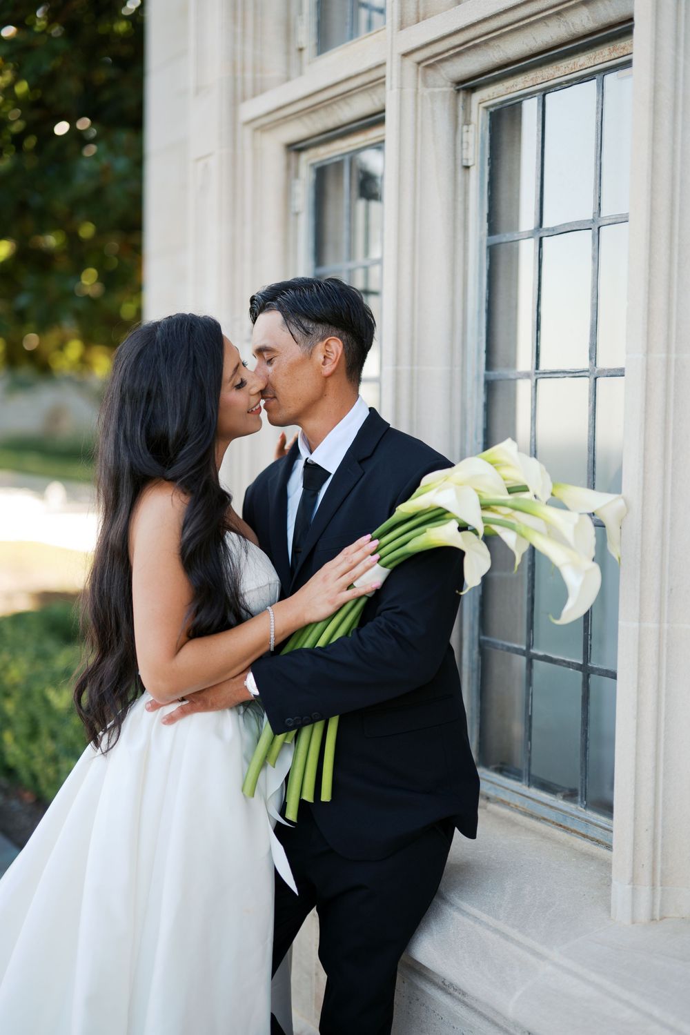 A romantic series of wedding photos showing a couple kissing against a white building with elegant windows.