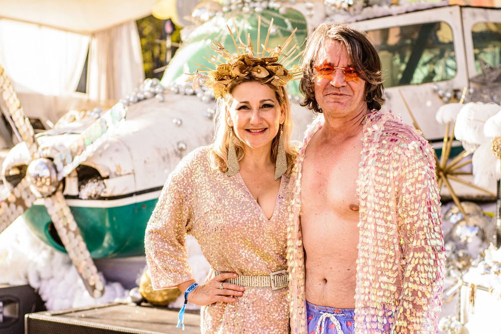 Festival attendees in sparkly and casual attire posing together at an outdoor event.
