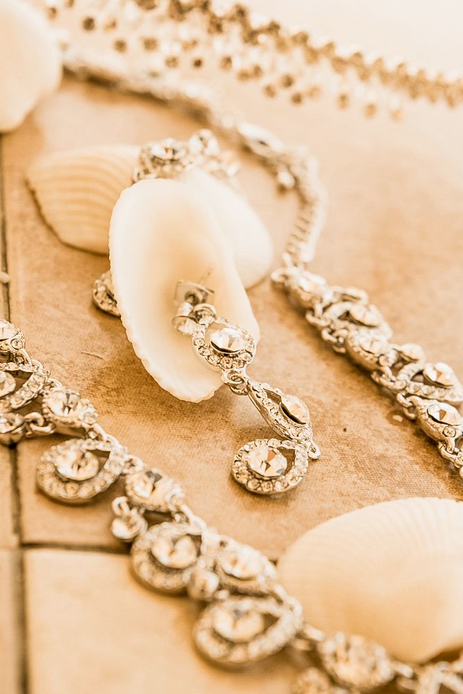 Elegant diamond jewelry pieces arranged in a row on beige textured surface in warm sepia tones.