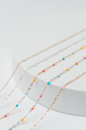 Colorful enamel jewelry chains displayed in clean luxury product photography for permanent jewelry brand in Jupiter Florida.