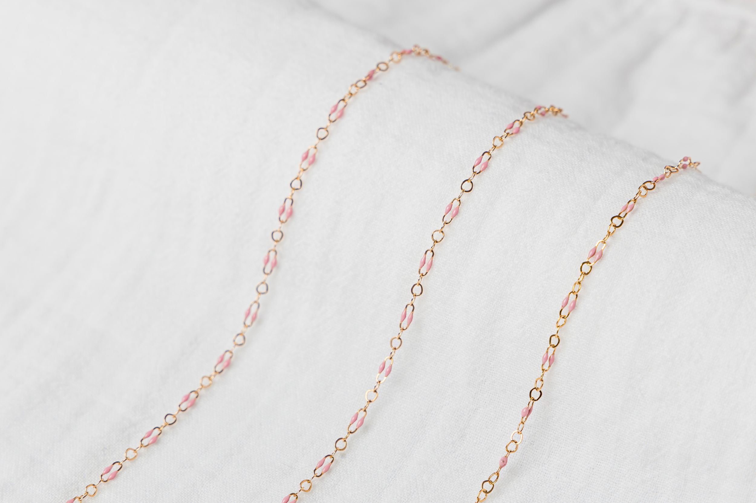 Pink enamel gold jewelry chain flat lay styled in feminine luxury product photography in Jupiter Florida studio.