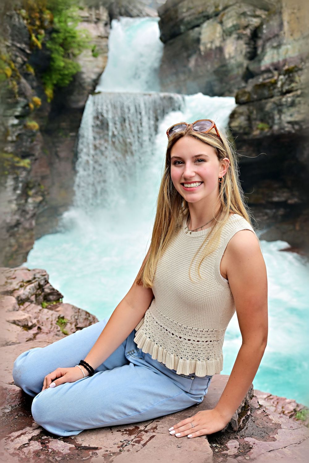 senior portrait of girl in front of waterfall with ice blue water glacier national park montana