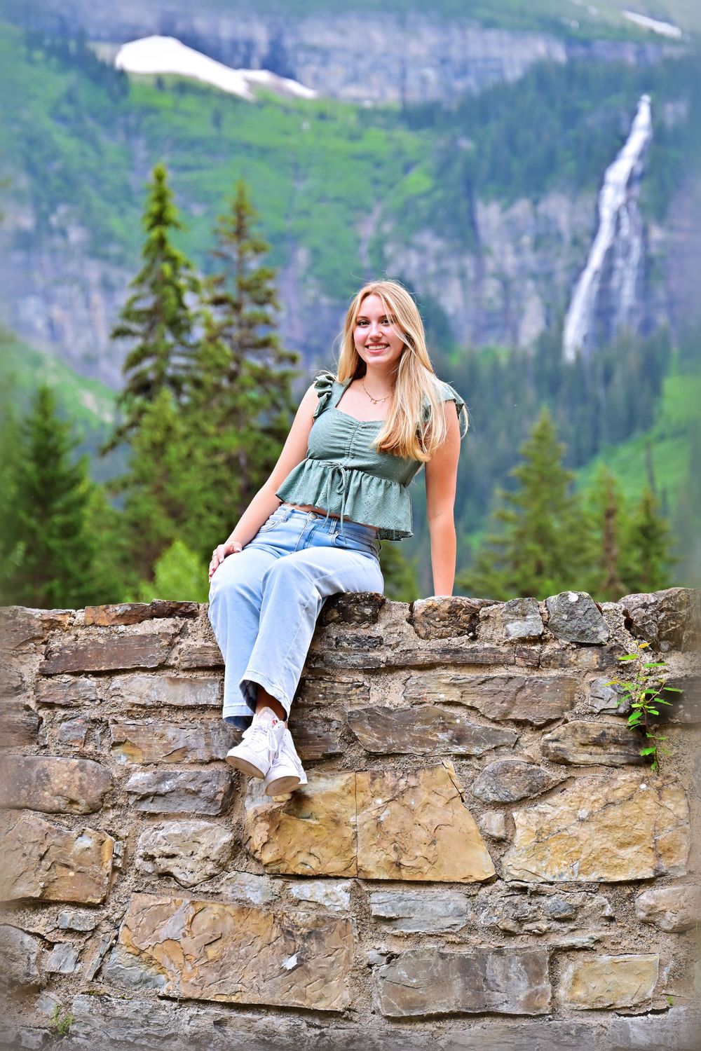 senior portrait of girl on a stone bridge with waterfall in the background glacier national park montana
