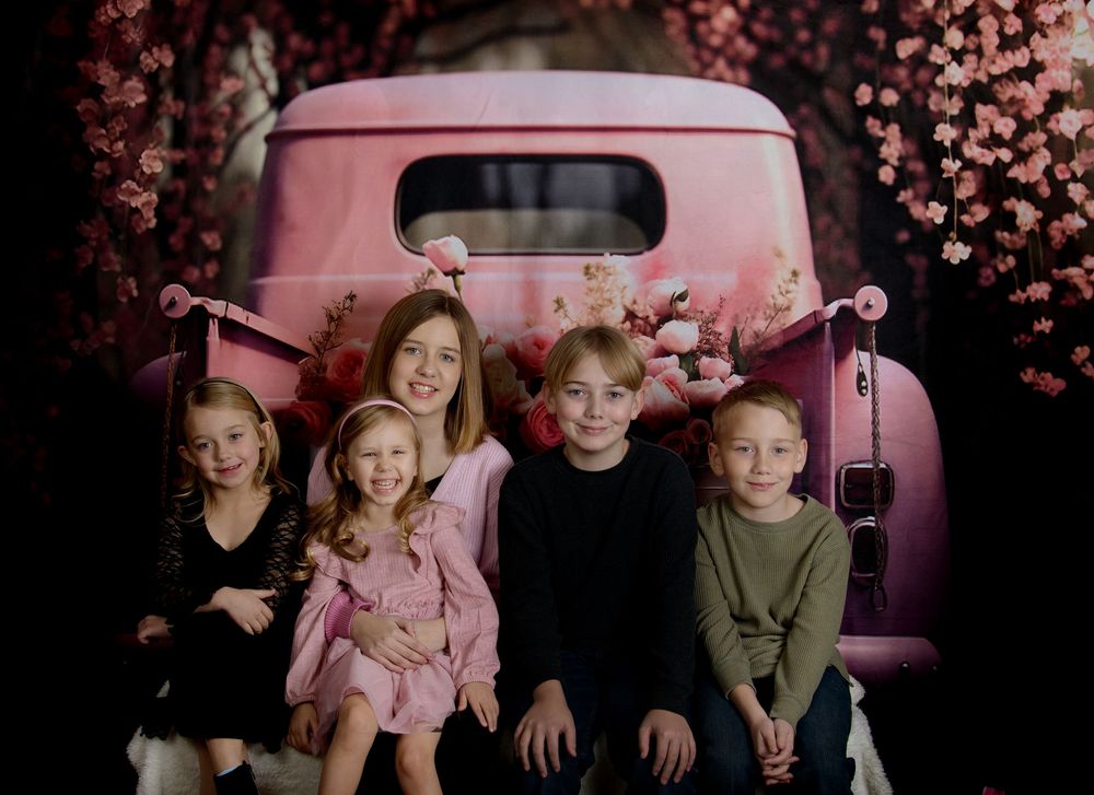 A family sits together on a dark background with pink cherry blossoms creating a dreamy atmosphere.