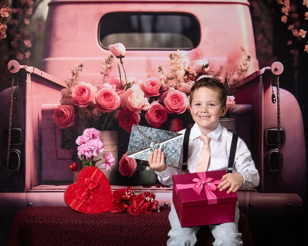 Vintage pink truck decorated with roses and Valentine's Day gifts creates a romantic holiday photo setting.