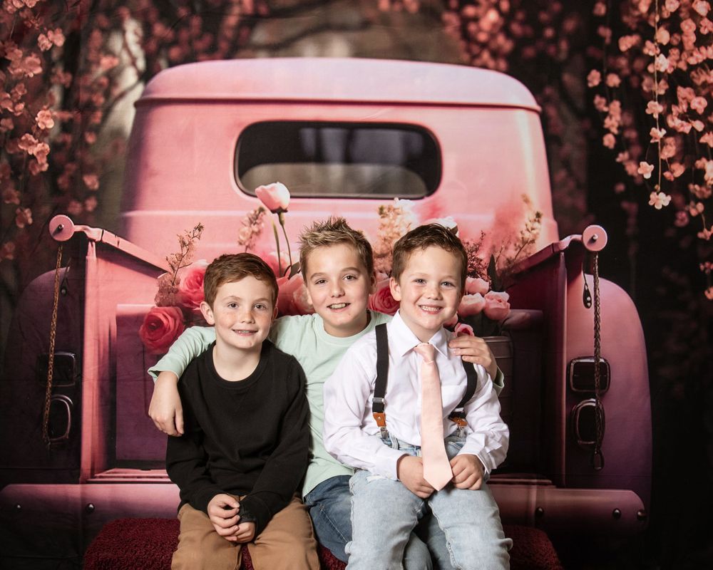 A series of children posing on a vintage pink car in different playful arrangements with a floral backdrop.